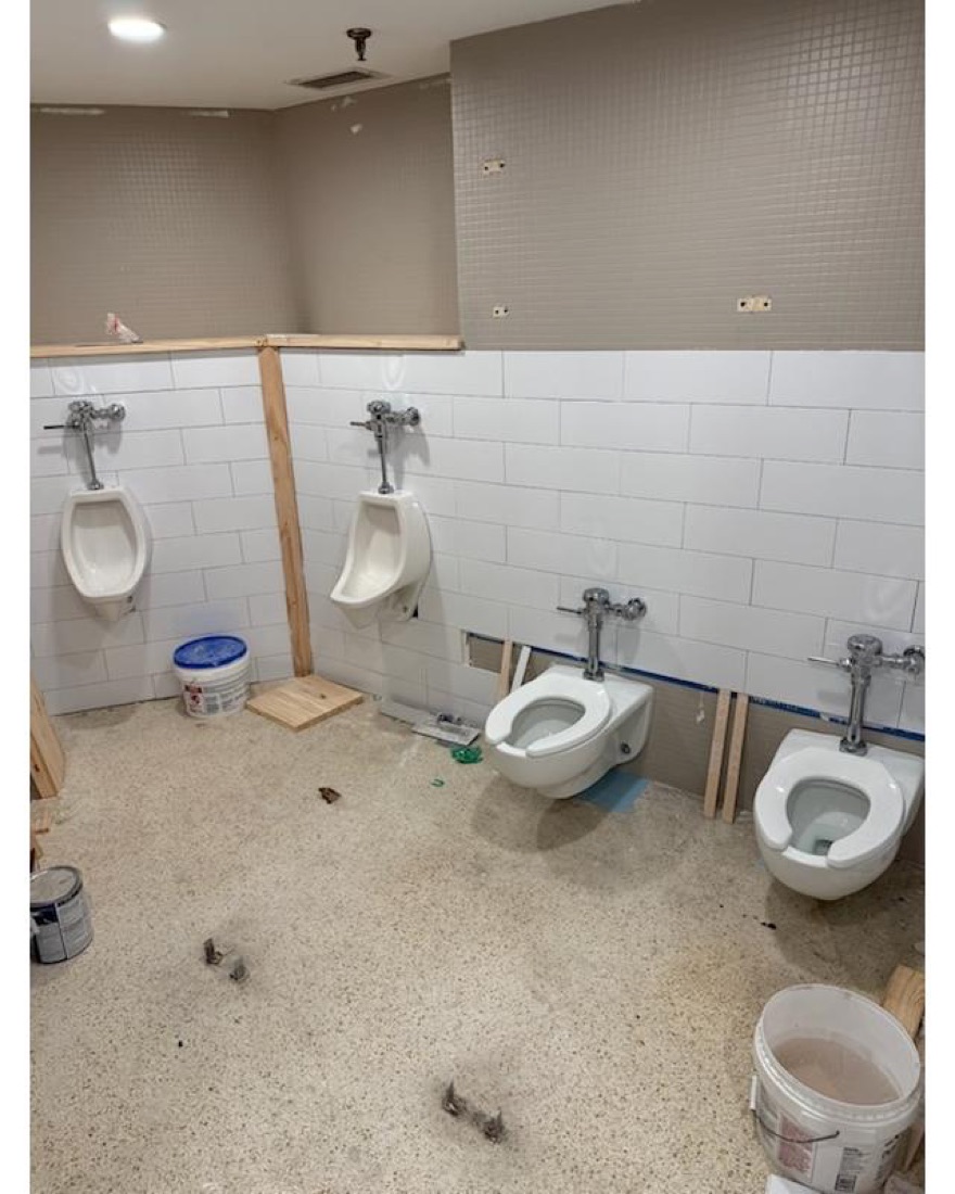 Commercial restroom under construction with urinals and wall-hung toilets installed