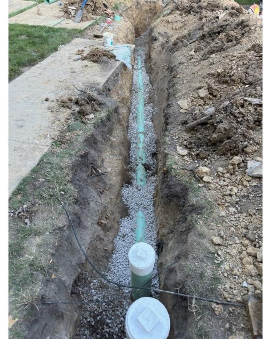 New sewer lateral bedded in stone in an open trench with two cleanouts set